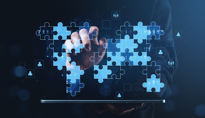 Business professional pointing at tablet with puzzle pieces representing cybersecurity strategy and business objectives