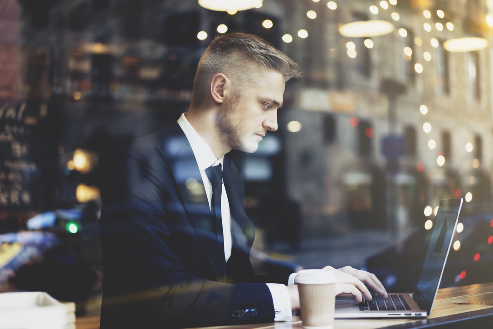 Business man remote working in a coffee shop using a secure Microsoft 365 environment