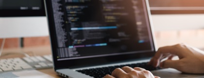 A close up a persons hands typing on a laptop updating their firewall rules
