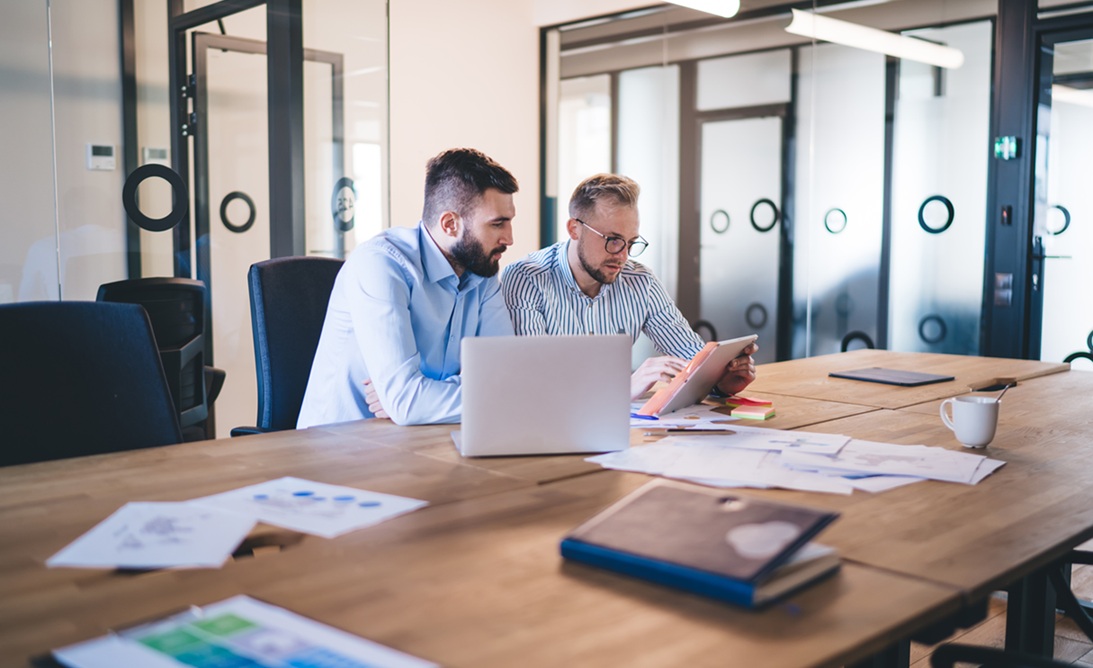 Two IT Team workers sitting at a board table reviewing their Incident Response Plan and Cyber Risk Register.