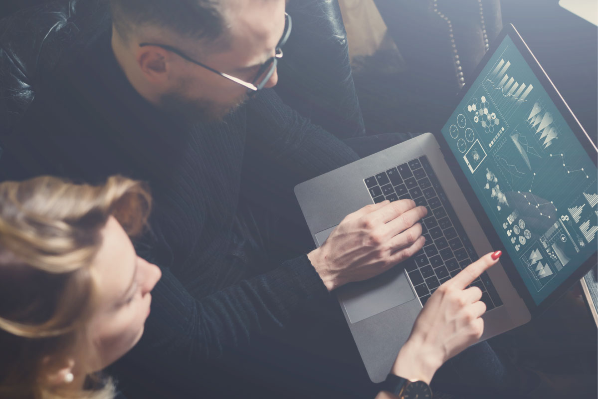Two professionals reviewing firewall security metrics and network data on a laptop during a firewall security review.