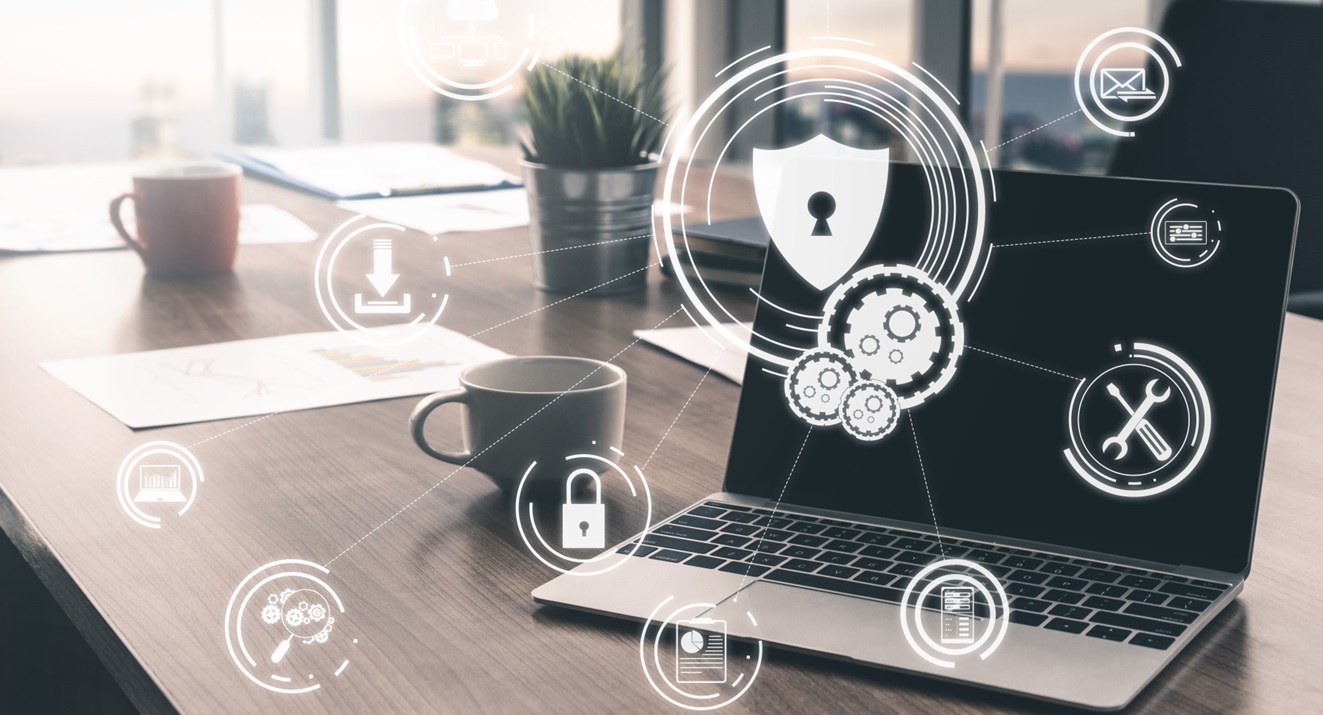 A laptop on a boardroom table with a holographic of an IT security shield leading to secured IT systems from a successful cybersecurity strategy