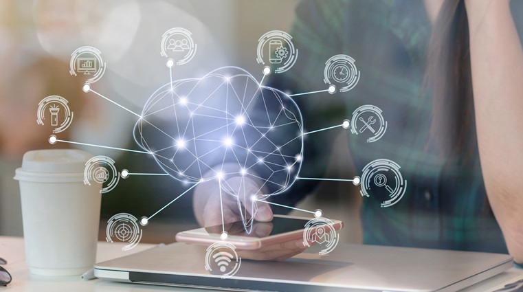 A woman with a laptop looking at her phone with a holographic of an artificial Intelligence brain 